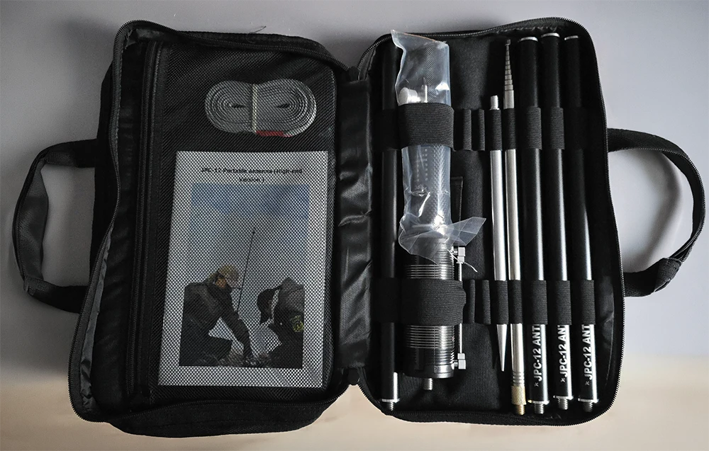 JPC-12 Vertikalantenne zerlegt in der Transporttasche auf dem Schreibtisch liegend. Tasche aufgeklappt, Teile der Antenne in den jeweiligen Schlaufen.